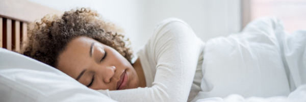 A woman sleeps soundly on her side at home.