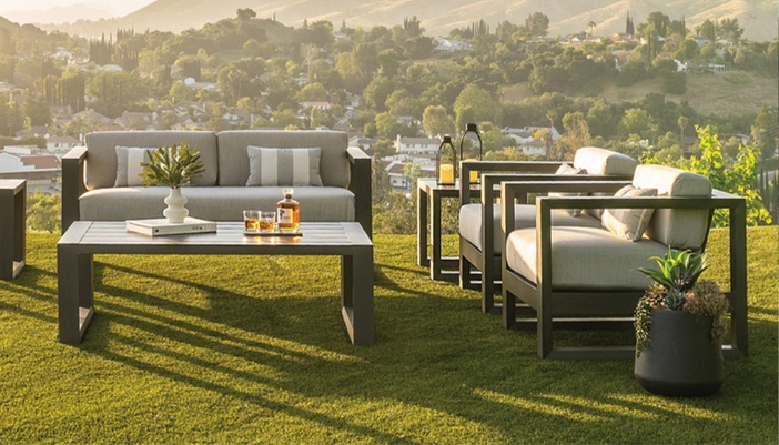 A set of gray patio furniture with a drink setup on a green surface.