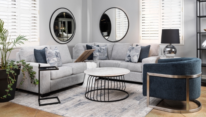 A modern living room with multiple mirrors and a gray L-shaped couch.