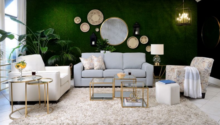 A modern living room with a bold green accent wall and neutral colored furniture.