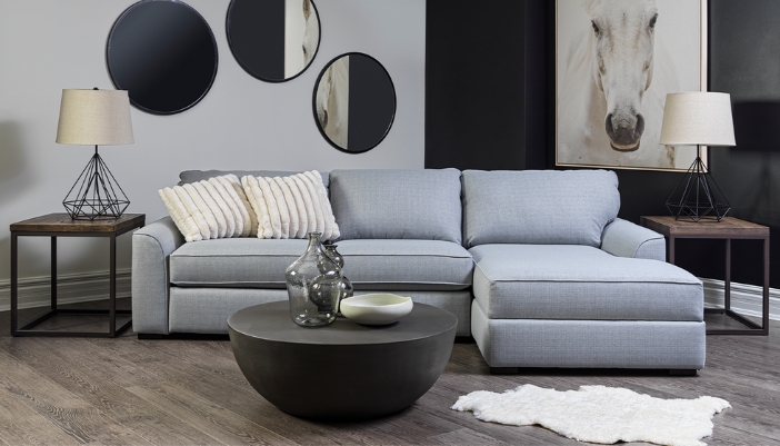 A modern living room with multiple mirrors and a gray L-shaped couch.