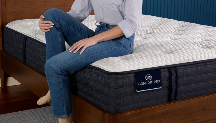 A person sits on a mattress at home