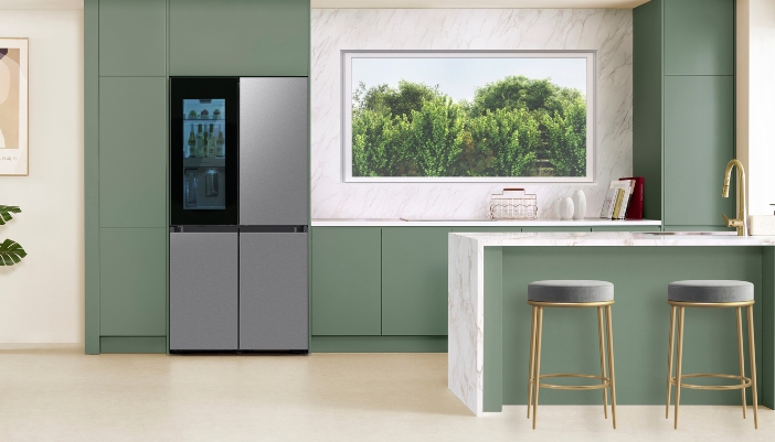A Samsung fridge in a modern green and silver kitchen.