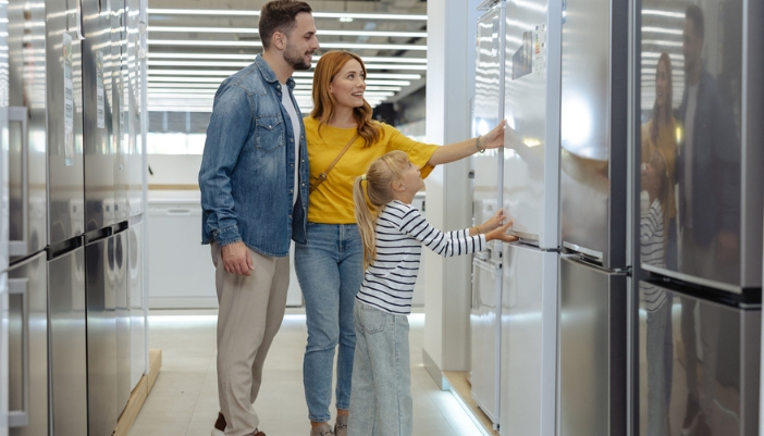 A family shops for a fridge in an appliance showroom.