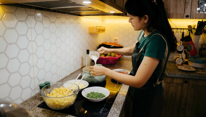 Woman cooking on induction stove with her ingredients on the stove