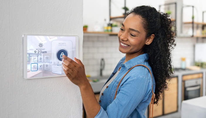 Closeup of a woman locking her home with a press of a button on a control panel