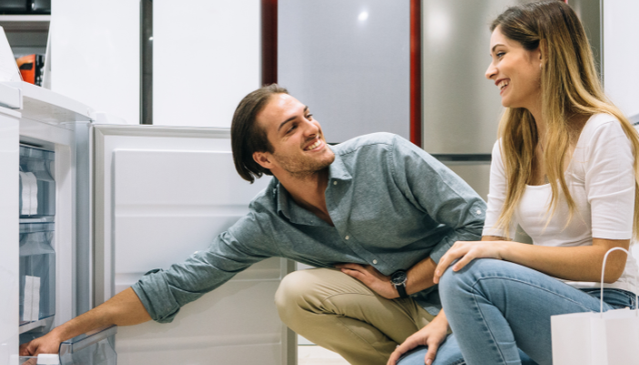 young couple looking at appliance features at an appliance store