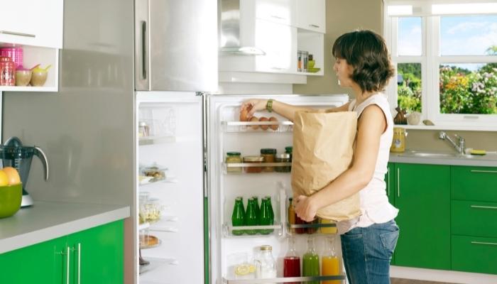 Woman putting groceries away in well-organized fridge