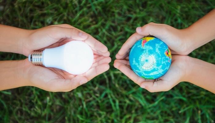 Hand holding lightbulb, next to hand holding a globe