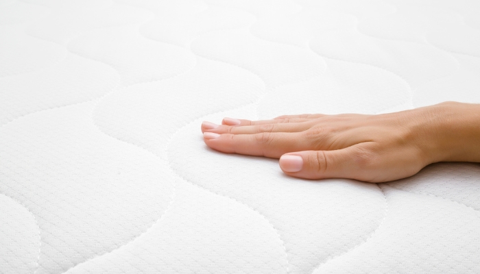 Closeup of hand testing out mattress surface