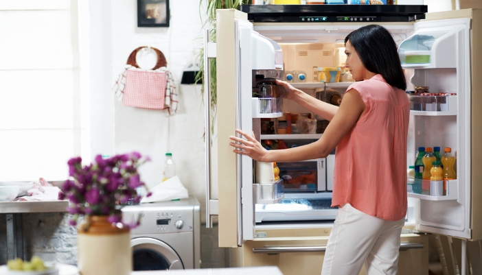 A woman putting something back in the fridge in an adapted compartemnt