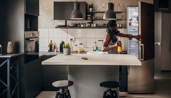A man putting away orange juice in the fridge in the same spot he always does