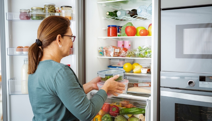 Woman putting leftovers away in the fridge