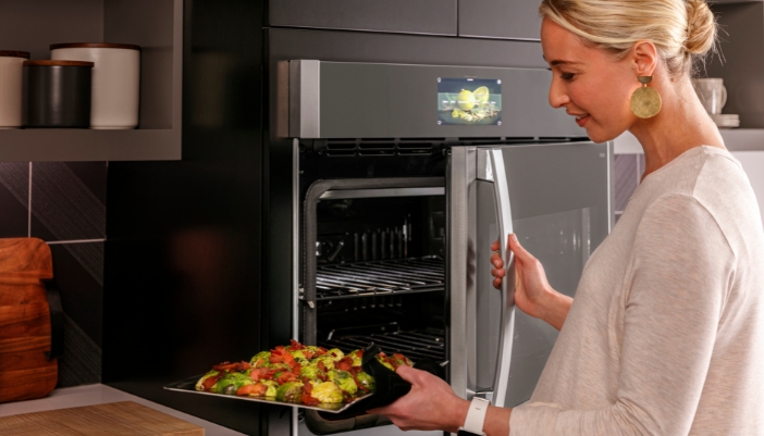 Woman putting dish into GE smart wall oven