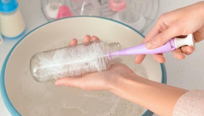 Closeup of hand cleaning bottle with bottle brush