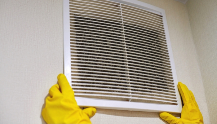Closeup of hands removing HVAC vent grate