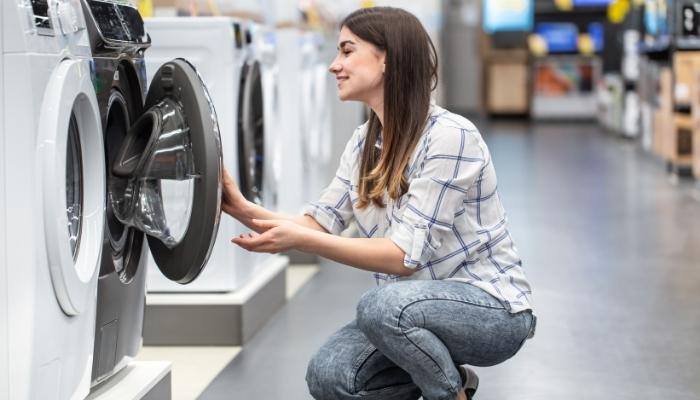 A young woman in a store chooses a washing machine