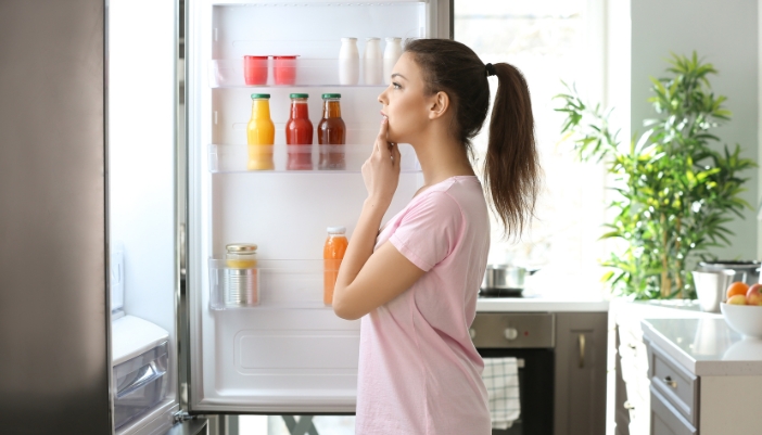 woman standing in front of open fridge