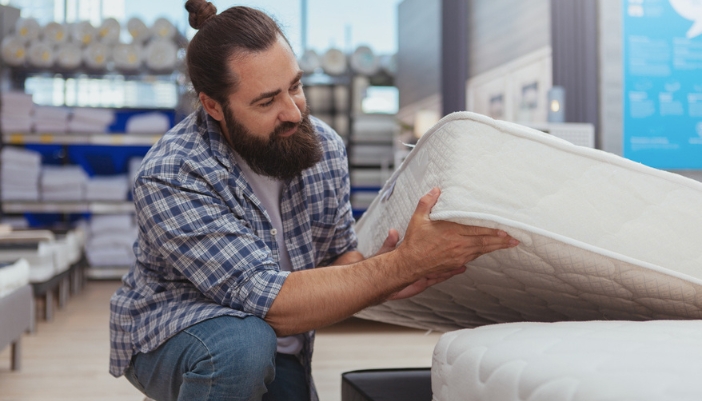 A mature man explores mattress options in a showroom.