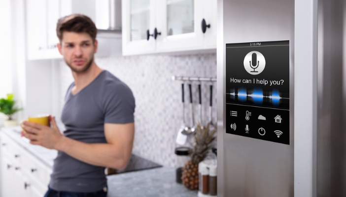 A man looks at his smart fridge in his kitchen. 