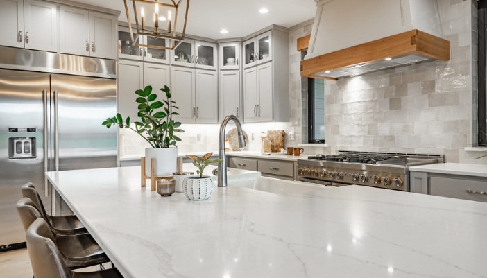 A modern white, granite kitchen with stainless steel appliances.