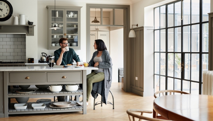 A couple sits together in their kitchen and looks around their space.
