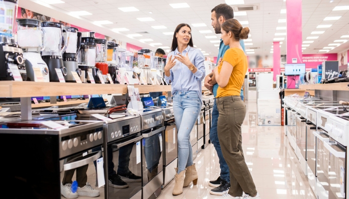 A couple works with a salesperson in an appliance showroom.