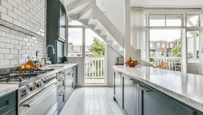 A luxury blue and white kitchen lit up by natural, bright daylight.