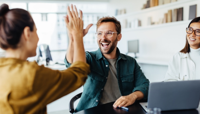 A team at work high fives after a success.