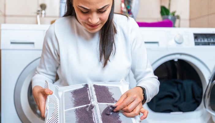 A woman cleans out her dryer trap at home.