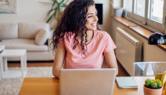 A woman works happily at her home laptop and gets her work done fast.