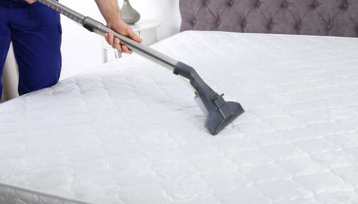 man vacuuming mattress