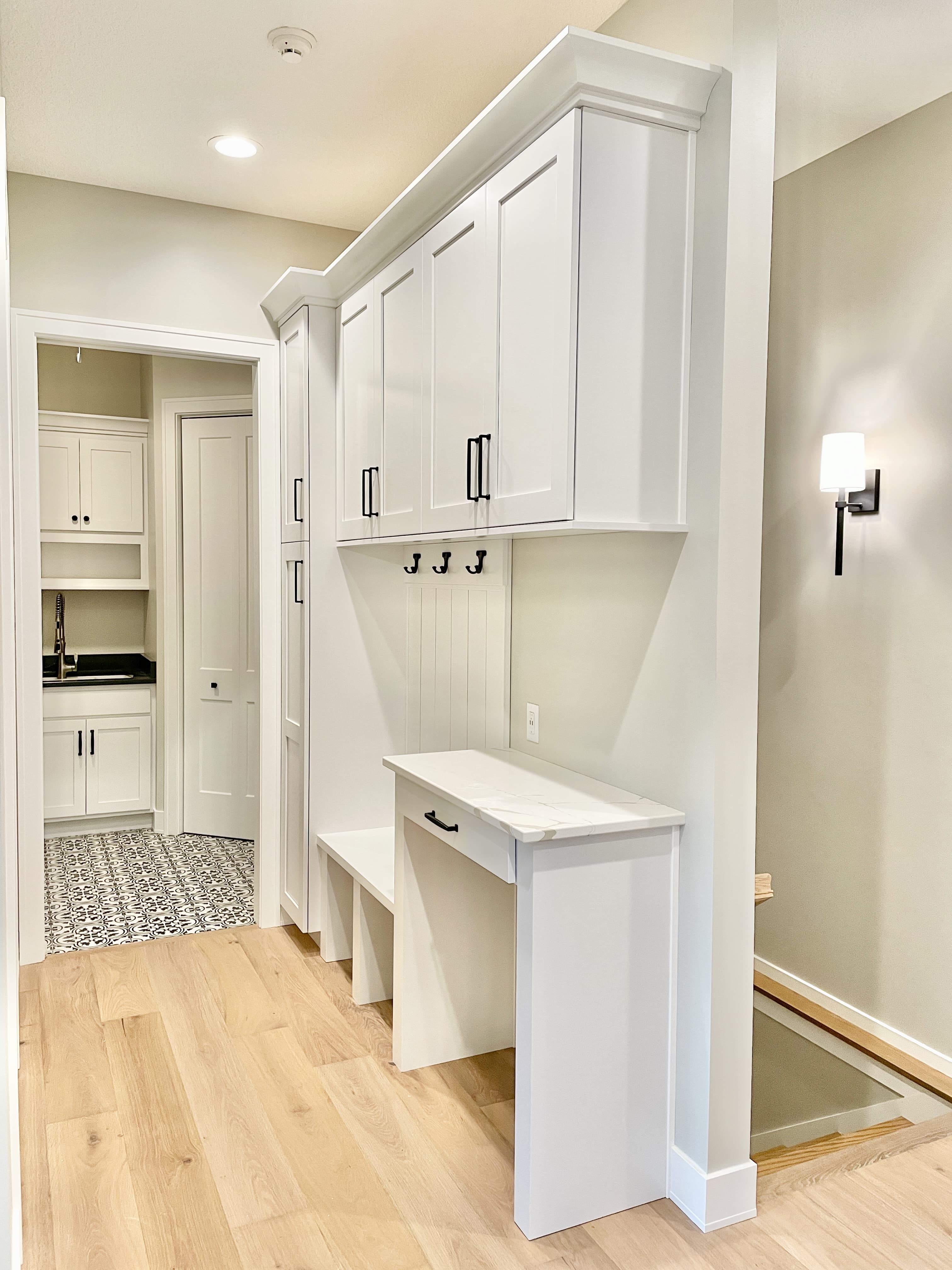 white cabinet drop zone bench area near back entry of home showing door to laundry room nearby