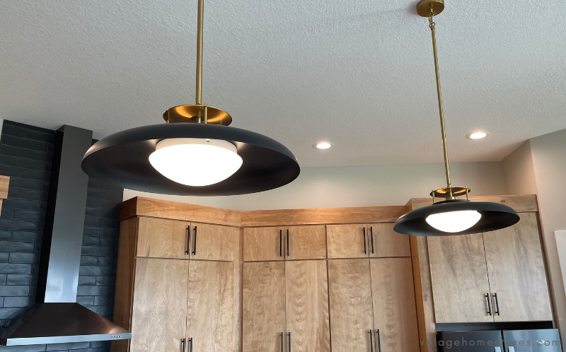 midcentury modern inspired pendant lights above kitchen island in warm brass and matte black finish