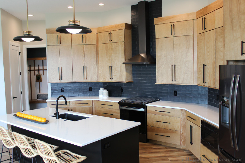 kitchen design in the quad cities from village home stores with light wood cabinets and black appliances and wall tile