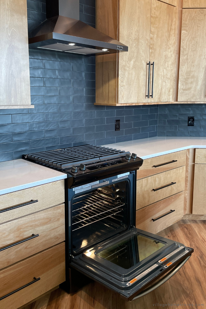 black stainless whirlpool appliances showing chimney wall mount hood and slide in range with gas cooktop and oven door open