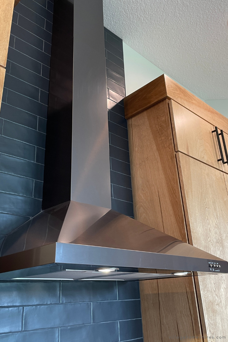 whirlpool black stainless steel chimney wall mount hood with extension installed over wall of black tile