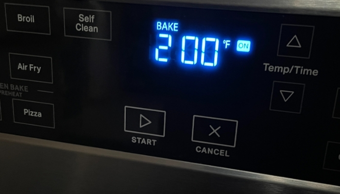 closeup image of stainless steel whirlpool range oven controls with blue LED display showing 200 degree F