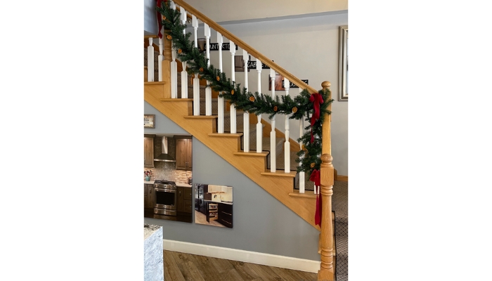 Oak and painted white staircase banister decorated for Christmas with pine garland, ribbon bows, and dried citrus slices