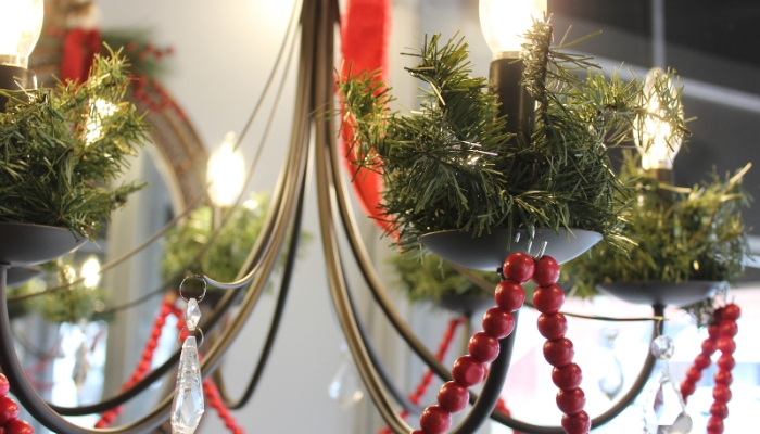 Close up image of Christmas garlands around chandelier light with faux cranberry strands on matte black chandelier