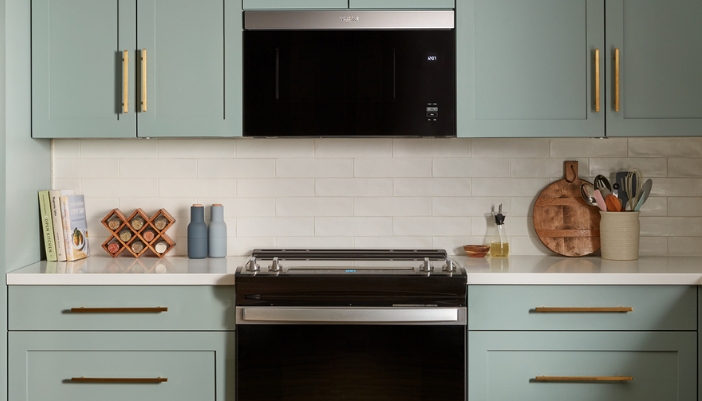 stainless steel whirlpool microwave hood installed in blue cabinet kitchen