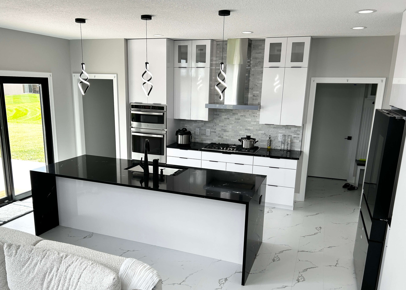 white cabinet modern kitchen design in Bettendorf iowa with black waterfall island counter from village home stores