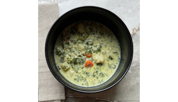 Overhead view image of spinach soup in a black ceramic bowl.