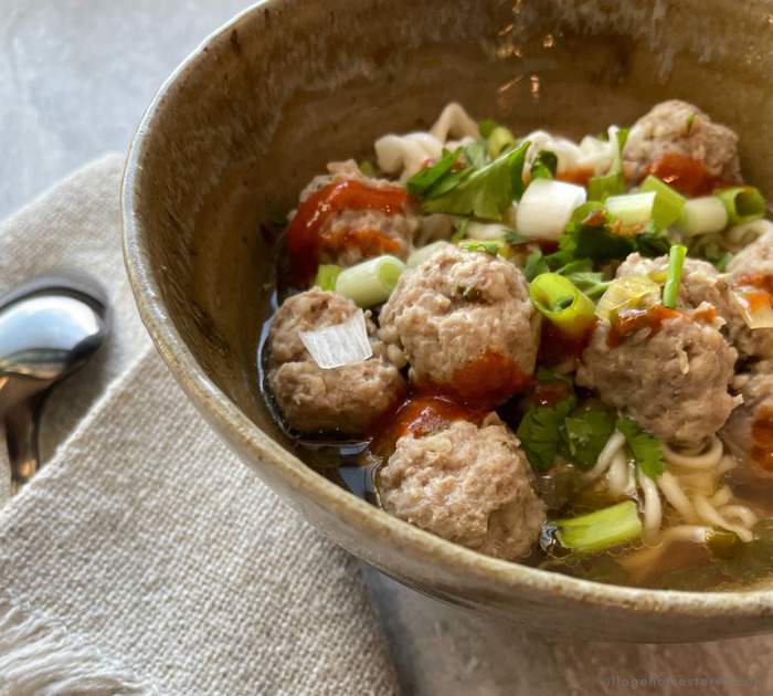 bowl of Thai meatball noodle soup topped with scallions and cilantro.