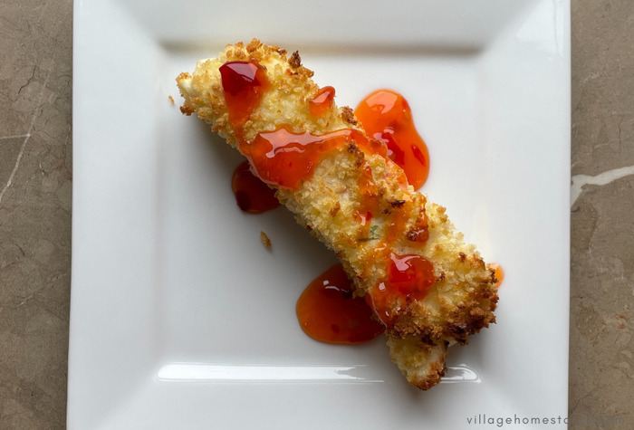 crab Rangoon crispy stick on white plate with red chili sauce drizzle