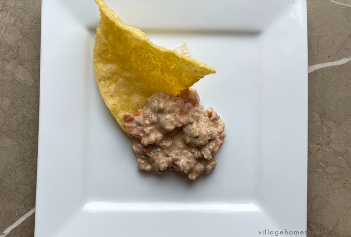 sausage dip and tortilla chip on white plate