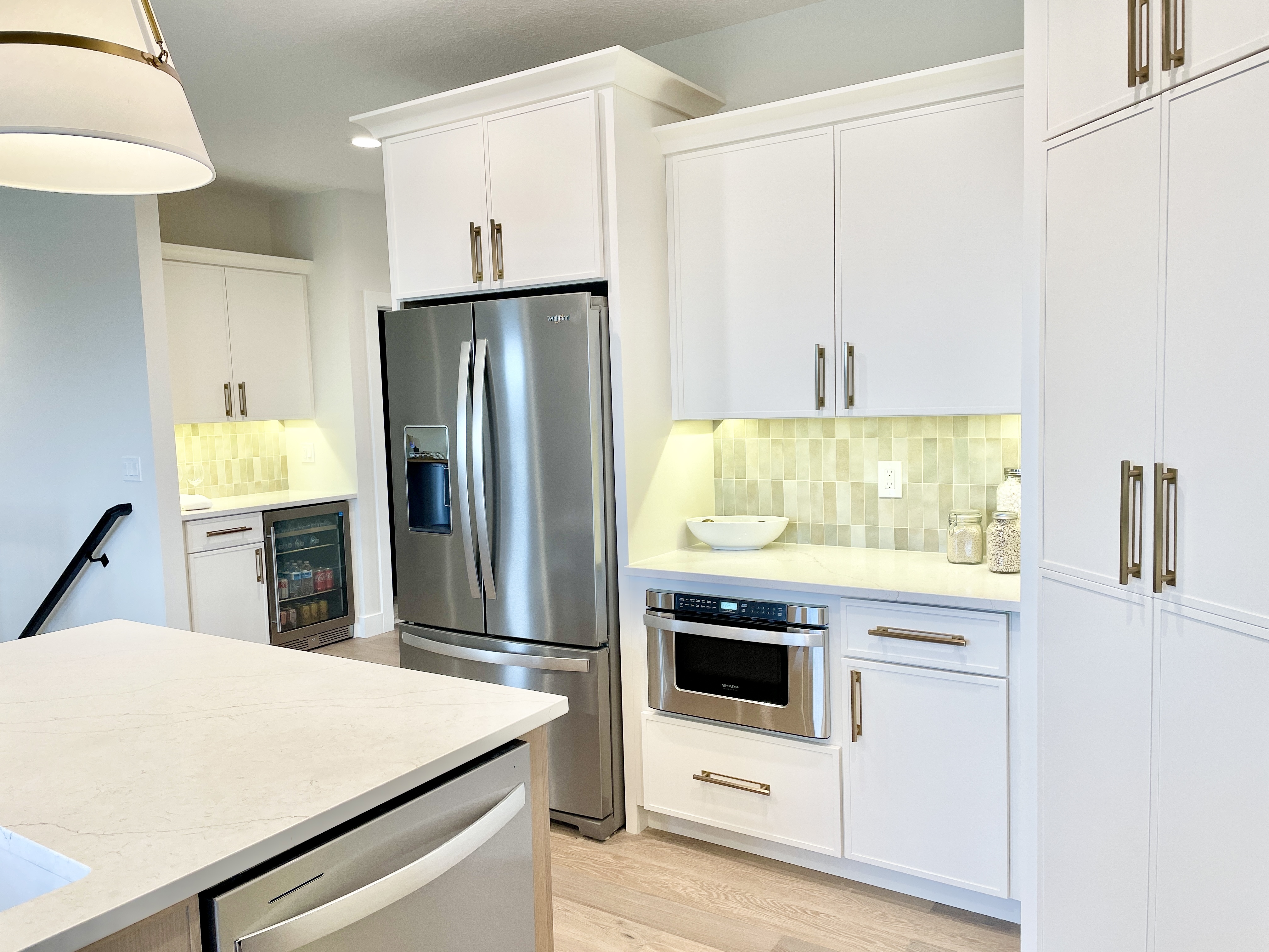 kitchen cabinetry with refrigerator microwave drawer and dry bar design in background