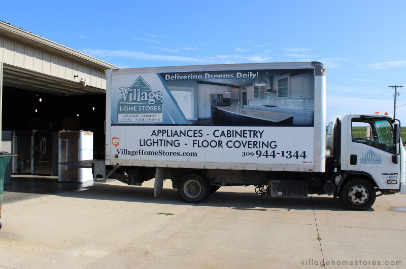 village home stores box truck at warehouse with logo and image on side