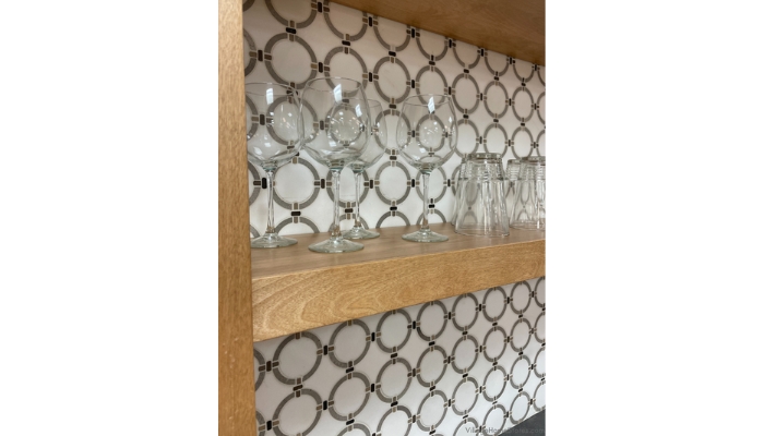 close up image of clear glassware on birch shelf with mosaic tile behind it