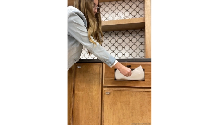 woman in denim jacket reaching for white paper towel from drawer dispense on bar cabinet